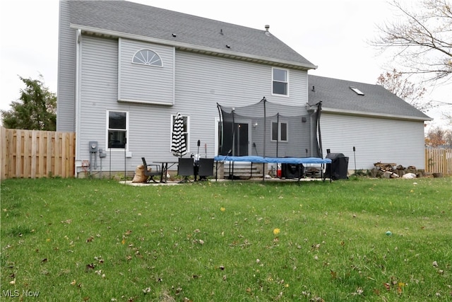 back of property featuring a yard and a trampoline