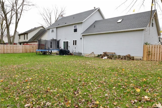 back of house featuring a yard and a trampoline