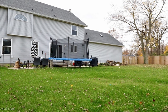 back of house featuring a lawn and a trampoline