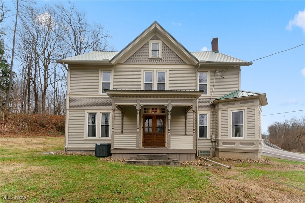 victorian house with covered porch, a front lawn, and central air condition unit