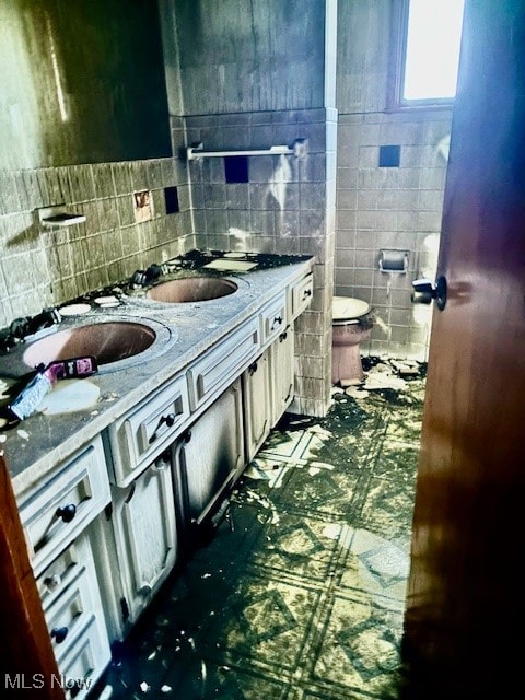 bathroom with toilet, vanity, tile patterned floors, and tile walls