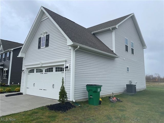 view of side of home with a garage, central air condition unit, and a yard