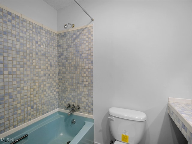 bathroom with toilet and tiled shower / bath