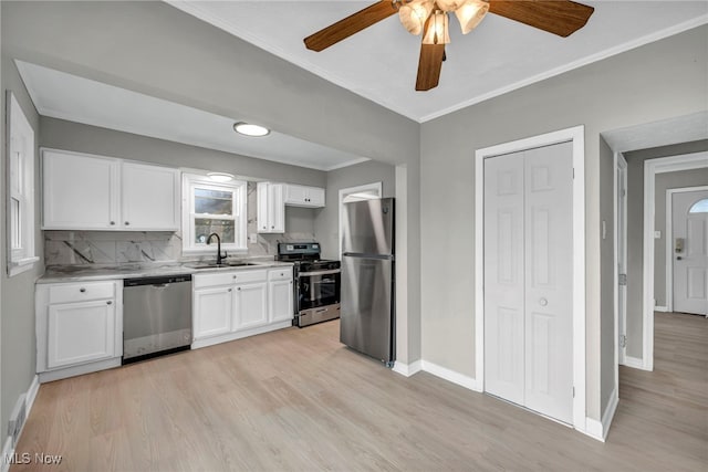 kitchen with white cabinets, backsplash, appliances with stainless steel finishes, and light hardwood / wood-style flooring