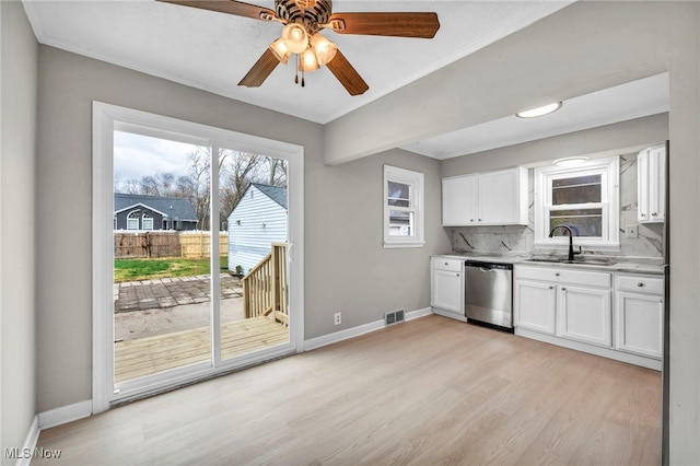 kitchen with white cabinetry, sink, light hardwood / wood-style flooring, stainless steel dishwasher, and decorative backsplash