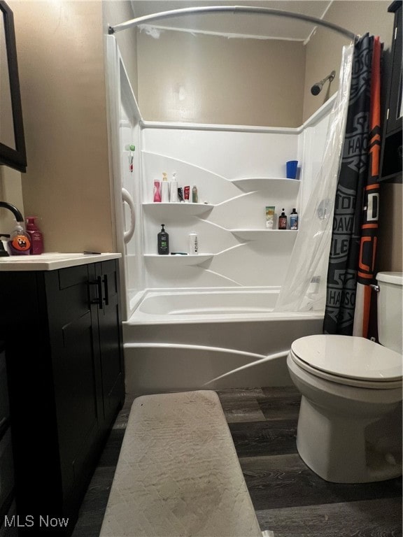 full bathroom with hardwood / wood-style floors, vanity, shower / bath combination with curtain, and toilet