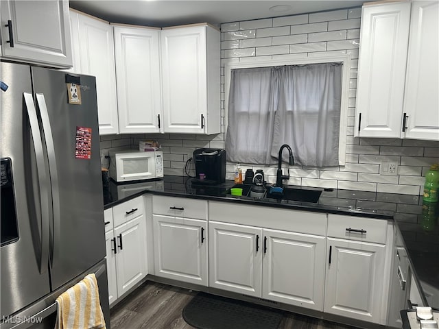 kitchen with white cabinetry, sink, dark wood-type flooring, stainless steel refrigerator with ice dispenser, and backsplash