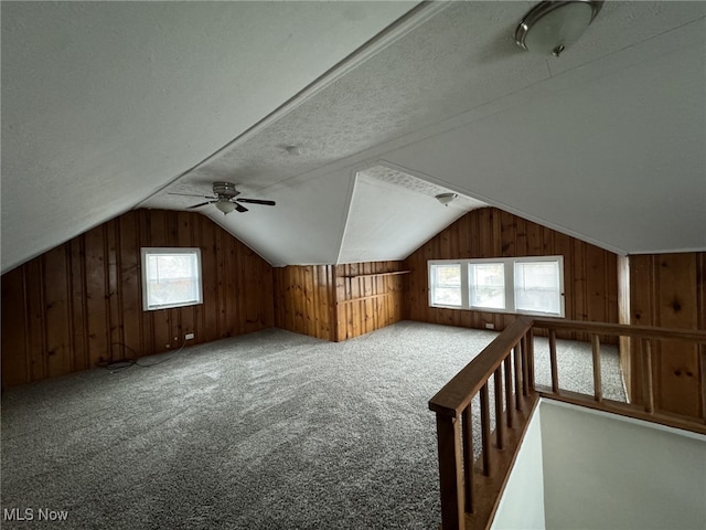 additional living space featuring a textured ceiling, wood walls, and vaulted ceiling