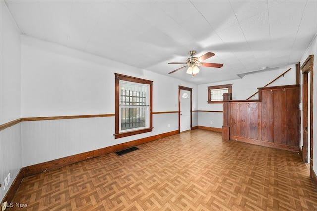 spare room featuring parquet flooring, ceiling fan, and wooden walls