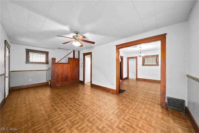 empty room with ceiling fan with notable chandelier and light parquet floors