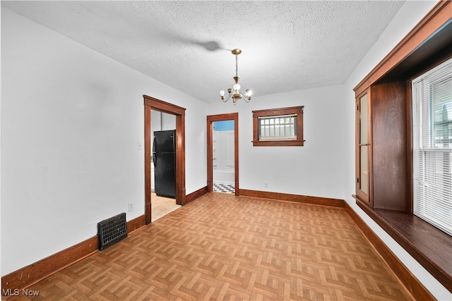 unfurnished room featuring light parquet flooring, a textured ceiling, and an inviting chandelier