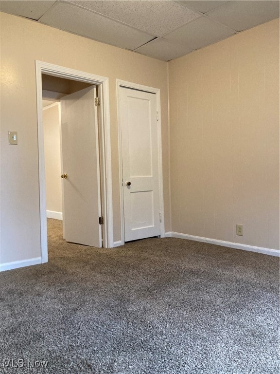 carpeted empty room featuring a drop ceiling