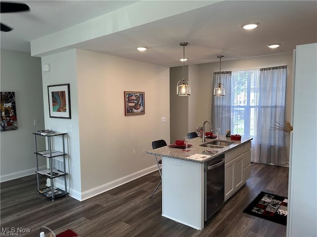 kitchen featuring pendant lighting, dark wood-type flooring, a center island with sink, stainless steel dishwasher, and white cabinetry