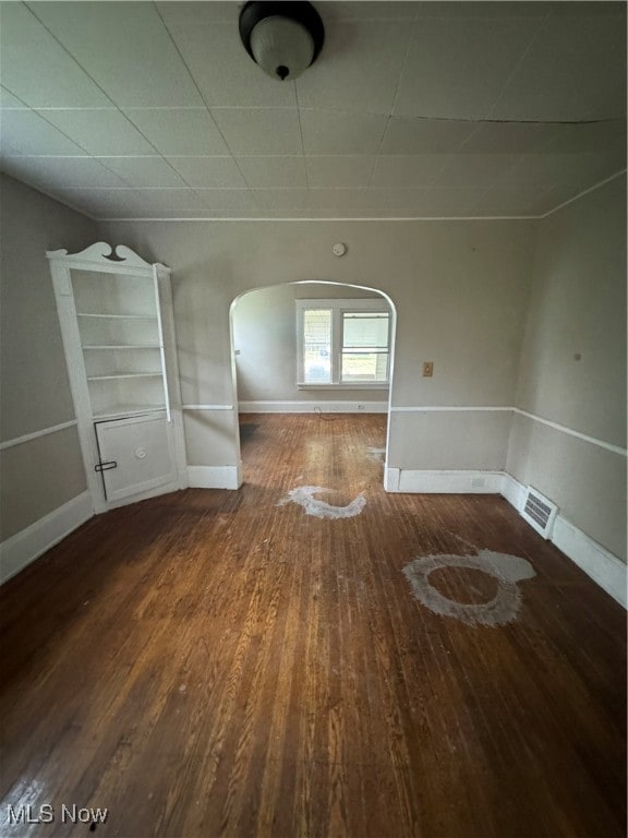 interior space with a paneled ceiling and dark hardwood / wood-style floors