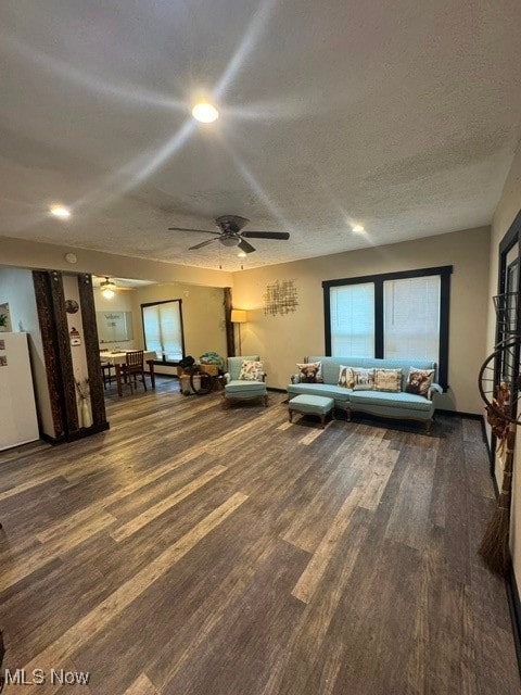 living room featuring hardwood / wood-style flooring, ceiling fan, and a textured ceiling