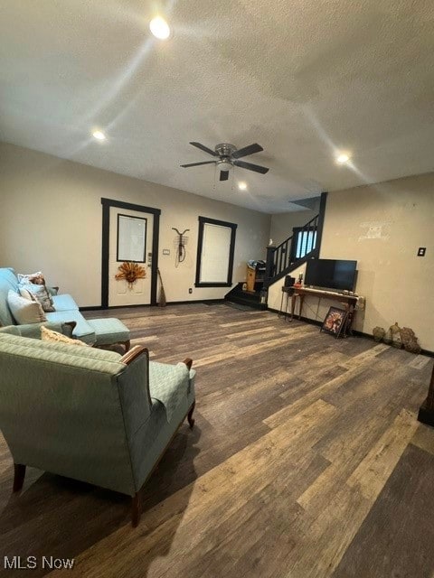 living room with hardwood / wood-style flooring, ceiling fan, and a textured ceiling