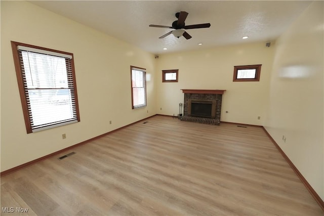 unfurnished living room with ceiling fan, a fireplace, and light hardwood / wood-style flooring