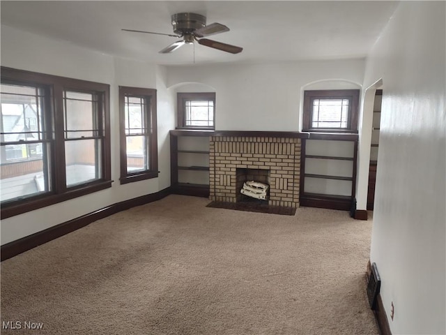 unfurnished living room with ceiling fan, carpet floors, a fireplace, and baseboards