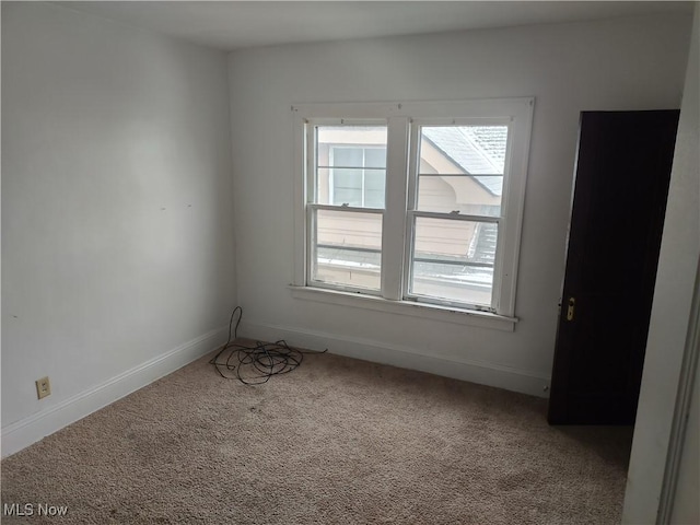 carpeted spare room featuring baseboards