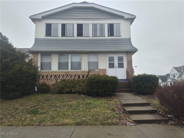 view of front facade with entry steps, a front lawn, and brick siding