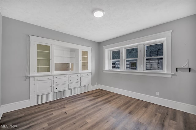 unfurnished room with a textured ceiling and dark wood-type flooring