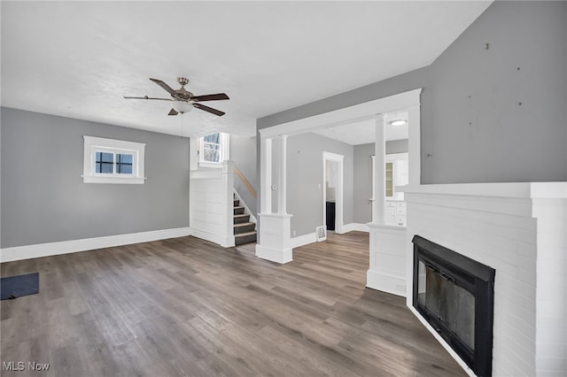 unfurnished living room with ceiling fan, dark hardwood / wood-style flooring, and a brick fireplace