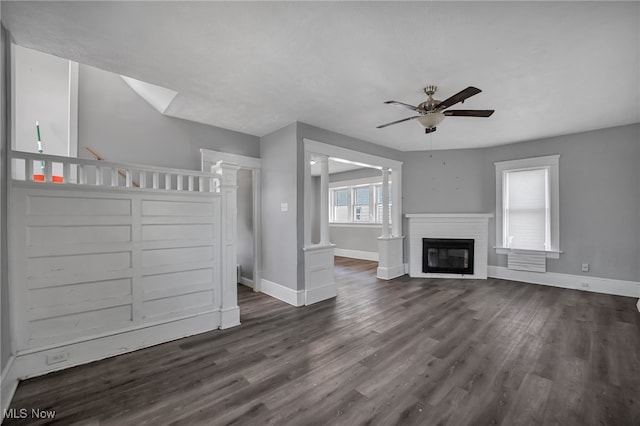 unfurnished living room with a fireplace, dark hardwood / wood-style flooring, and ceiling fan