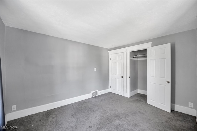 unfurnished bedroom featuring a closet and dark carpet