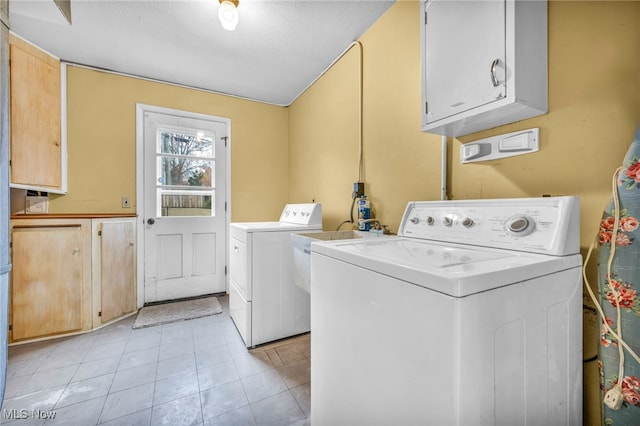 washroom featuring light tile patterned flooring, cabinets, a textured ceiling, and washing machine and clothes dryer