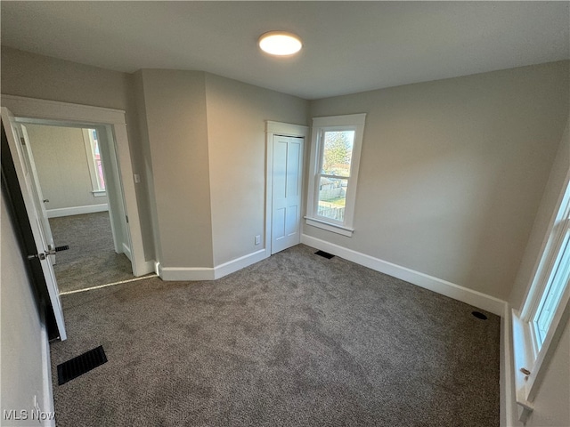 unfurnished bedroom with a closet and dark colored carpet