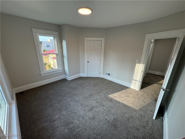 unfurnished bedroom featuring a closet and dark colored carpet