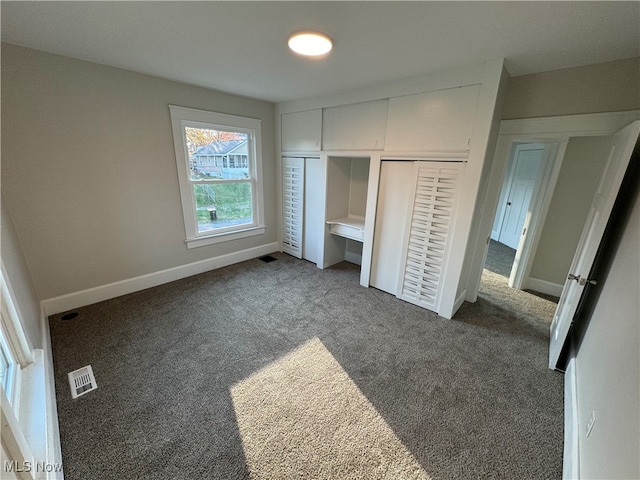 unfurnished bedroom featuring dark carpet and a closet