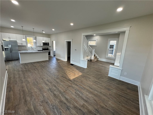 kitchen with a wealth of natural light, stainless steel appliances, pendant lighting, a center island, and white cabinetry