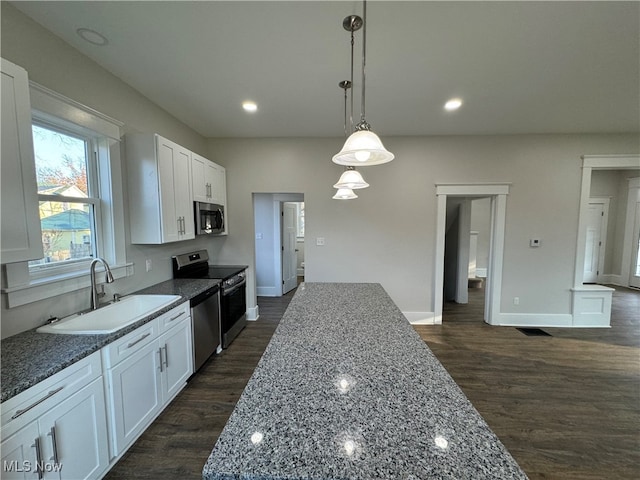 kitchen featuring white cabinetry, sink, stainless steel appliances, dark stone countertops, and decorative light fixtures