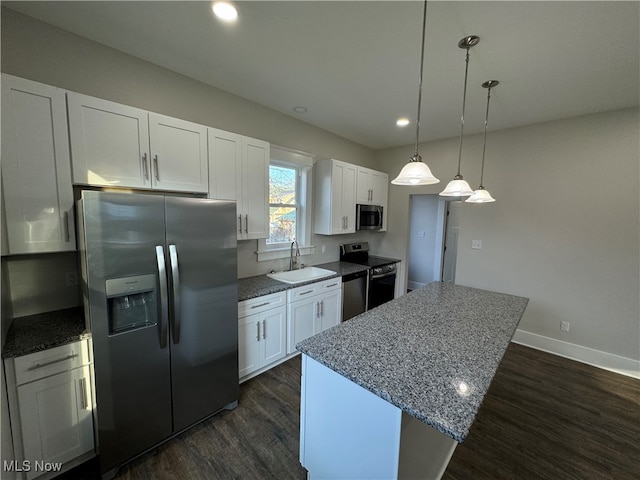 kitchen featuring sink, stainless steel appliances, light stone counters, decorative light fixtures, and white cabinets