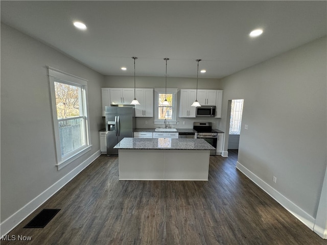 kitchen featuring white cabinetry, a center island, dark wood-type flooring, stainless steel appliances, and pendant lighting