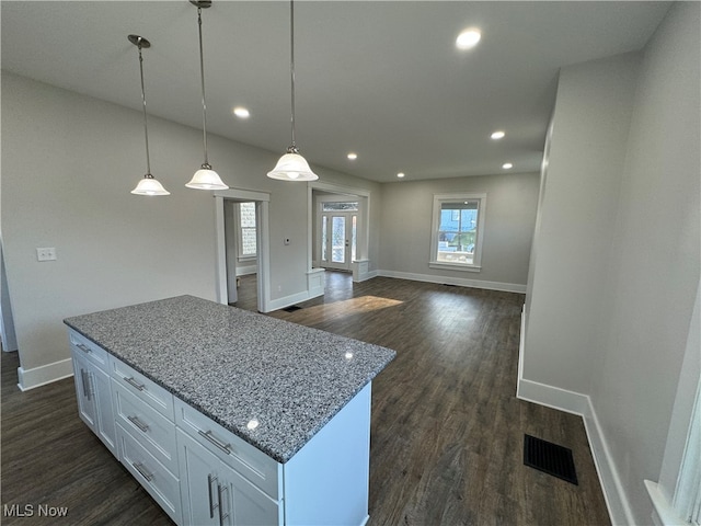 kitchen featuring white cabinets, pendant lighting, dark hardwood / wood-style floors, and light stone counters