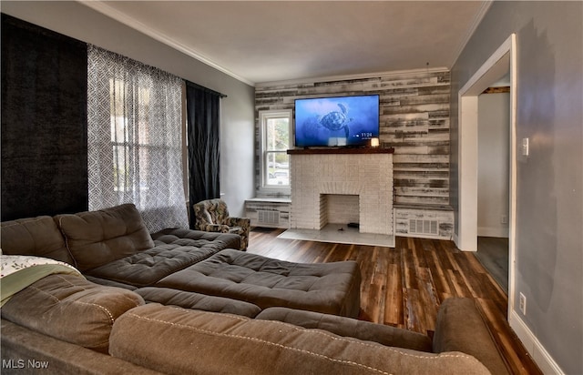 living room featuring wood-type flooring, crown molding, and a brick fireplace