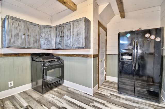 kitchen with black appliances, vaulted ceiling with beams, light wood-type flooring, and wooden walls