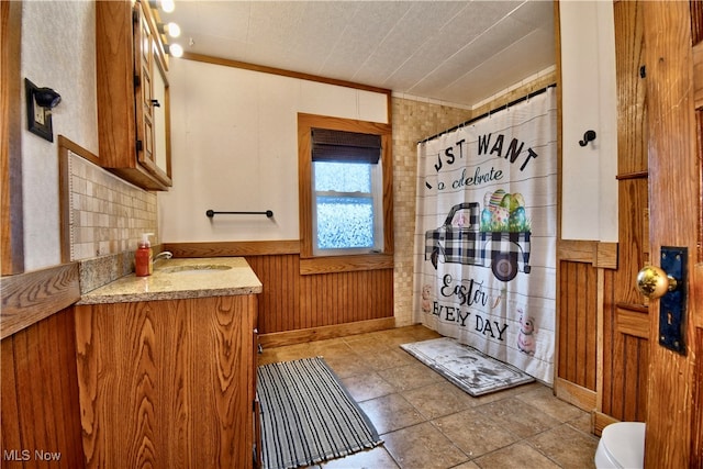 bathroom featuring vanity, toilet, ornamental molding, and wooden walls