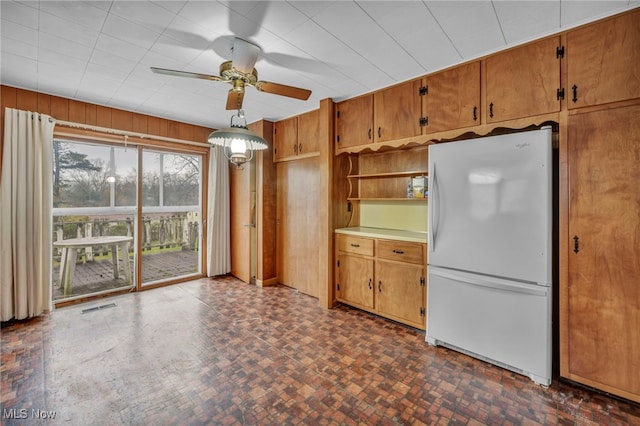 kitchen featuring wood walls, ceiling fan, and white refrigerator