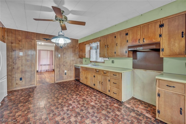 kitchen with ceiling fan, sink, stainless steel dishwasher, white refrigerator, and wood walls