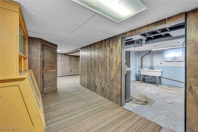 hall with wooden walls, sink, and concrete floors