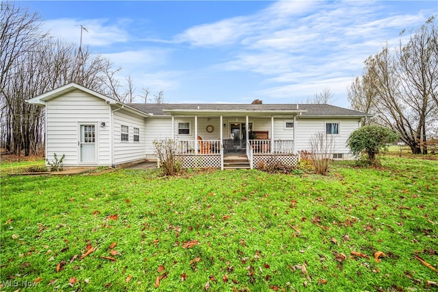 rear view of house with covered porch and a lawn