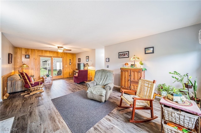 living room with wood-type flooring, ceiling fan, and wooden walls