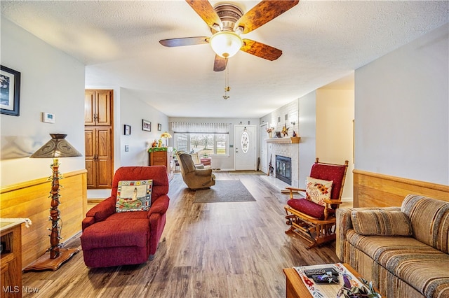 living room featuring hardwood / wood-style floors, a textured ceiling, ceiling fan, and wooden walls