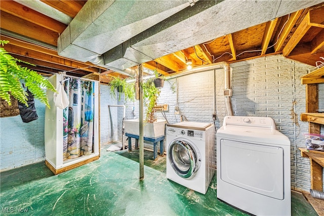 clothes washing area with brick wall and washing machine and clothes dryer