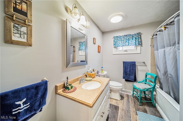 full bathroom featuring vanity, shower / bath combination with curtain, hardwood / wood-style flooring, toilet, and a textured ceiling