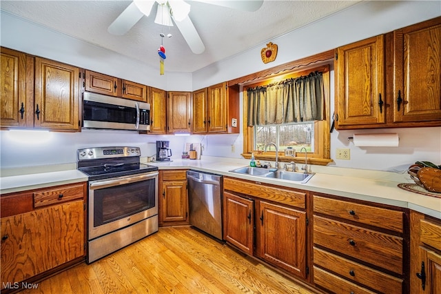 kitchen featuring sink, ceiling fan, a textured ceiling, appliances with stainless steel finishes, and light hardwood / wood-style floors