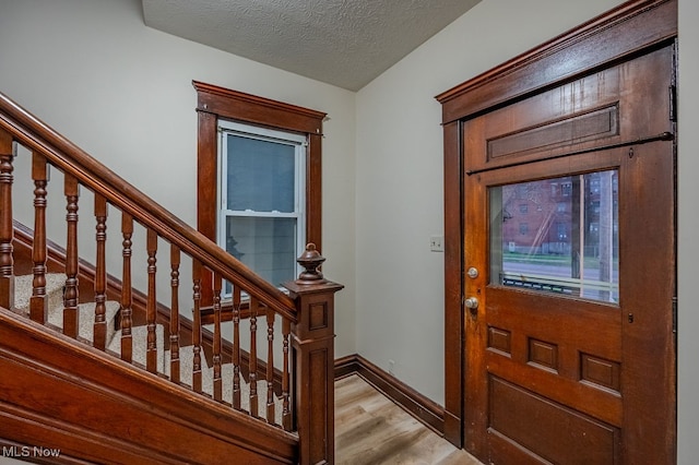 foyer entrance featuring a textured ceiling and light hardwood / wood-style flooring